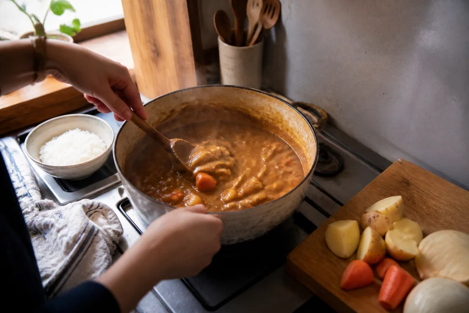 家庭の台所で、玉ねぎとにんじんを炒めて日本カレーを作る途中